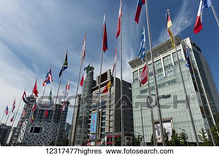 Stock Photograph - Modern buildings with digital screens for advertising and international flags on poles in a row; Seoul, South Korea. Fotosearch