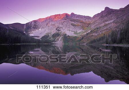 Stock Image - Mountain at sunset viewed across calm lake. Fotosearch