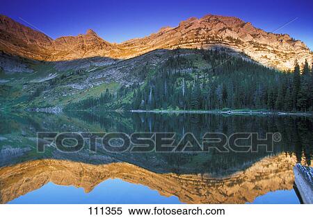 Stock Photography - Mountain at sunset viewed across calm lake. Fotosearch