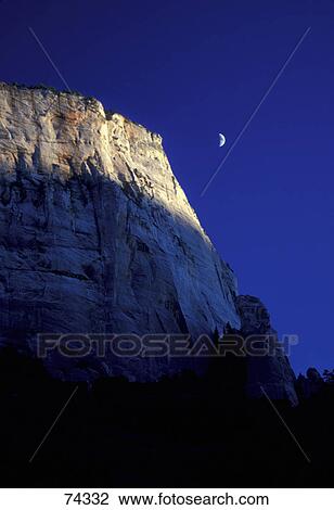 Stock Image - Mountain cliff with deep blue sky and quarter moon Zion National Park. Fotosearch
