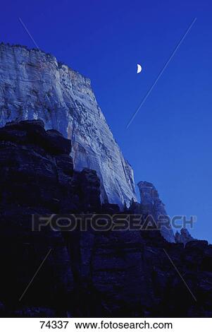 Stock Photo - Mountain cliff with deep blue sky and quarter moon Zion National Park. Fotosearch