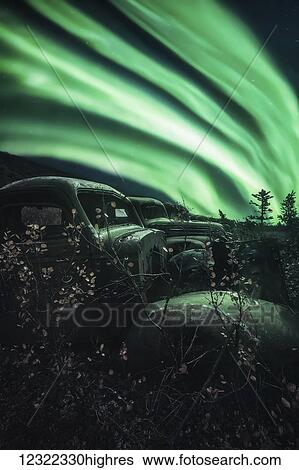 Stock Photograph - Northern lights overtop of abandoned trucks up the North Canol Road; Yukon, Canada. Fotosearch