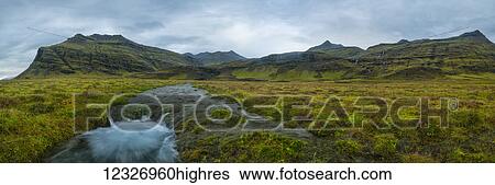 Stock Photograph - Panoramic view of a meltwater stream coming from the mountains along the south coast of Iceland; Iceland. Fotosearch