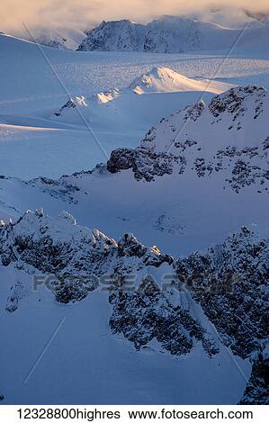Stock Photograph - Peaks of a snow covered mountain range glowing at sunset, Kachemak Bay State Park; Alaska, United States of America. Fotosearch