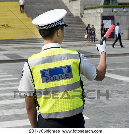 Stock Photograph - Policeman directing traffic at a crosswalk; Seoul, South Korea. Fotosearch