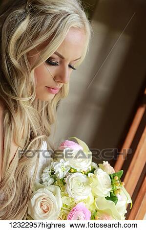 Stock Photograph - Portrait of a bride with long, blond hair and a flower bouquet; Oregon, United States of America. Fotosearch