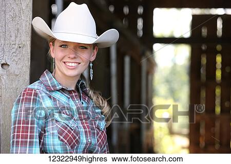 Stock Photograph - Portrait of a cowgirl in a white cowboy hat; Oregon, United States of America. Fotosearch