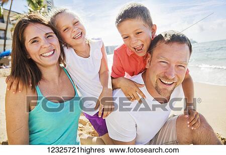 Stock Photograph - Portrait of a family of four enjoying a summer vacation in Waikiki Beach; Honolulu, Oahu, Hawaii, United States of America. Fotosearch