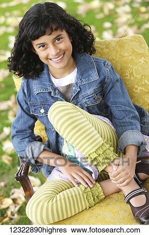 Stock Photograph - Portrait of a girl sitting on a chair; Oregon, United States of America. Fotosearch