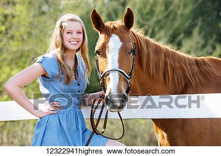 Stock Photograph - Portrait of a girl standing with her horse; Oregon, United States of America. Fotosearch