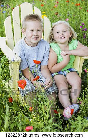 Portrait of a young boy and girl sitting together in an adirondack chair surrounded by colourful wildflowers in a field; Oregon, United States of America View Large Photo Image Stock Photograph - Portrait of a young boy and girl sitting together in an adirondack chair surrounded by colourful wildflowers in a field; Oregon, United States of America. Fotosearch