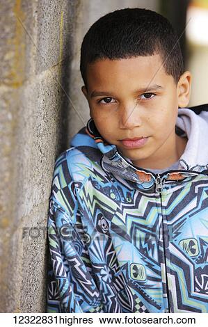 Stock Photograph - Portrait of a young boy standing against a concrete wall; Oregon, United States of America. Fotosearch