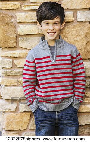 Stock Photograph - Portrait of a young boy standing against a stone wall; Oregon, United States of America. Fotosearch