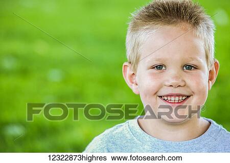 Stock Photograph - Portrait of a young boy with a grass field in the background; Oregon, United States of America. Fotosearch