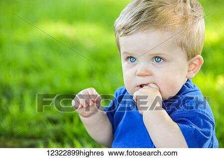Portrait of a young boy with blond hair and bright blue eyes chewing his finger and a grass field in the background; Oregon, United States of America View Large Photo Image Stock Photograph - Portrait of a young boy with blond hair and bright blue eyes chewing his finger and a grass field in the background; Oregon, United States of America. Fotosearch
