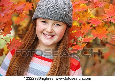 Stock Photograph - Portrait of a young girl with autumn coloured foliage behind her; Oregon, United States of America. Fotosearch