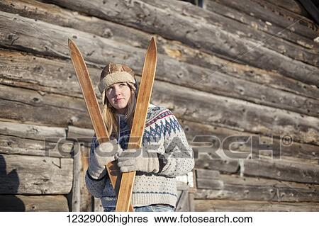 Portrait of a young woman holding wooden skis by a log cabin; Homer, Alaska, United States of America View Large Photo Image Stock Photograph - Portrait of a young woman holding wooden skis by a log cabin; Homer, Alaska, United States of America. Fotosearch