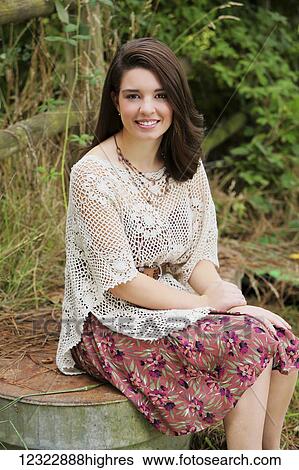 Stock Photograph - Portrait of a young woman sitting on a stone ledge; Oregon, United States of America. Fotosearch