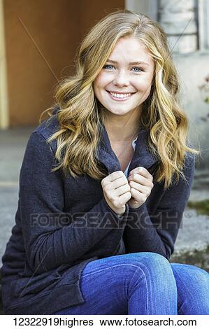 Stock Photograph - Portrait of a young woman sitting on a step in front of a building; Oregon, United States of America. Fotosearch
