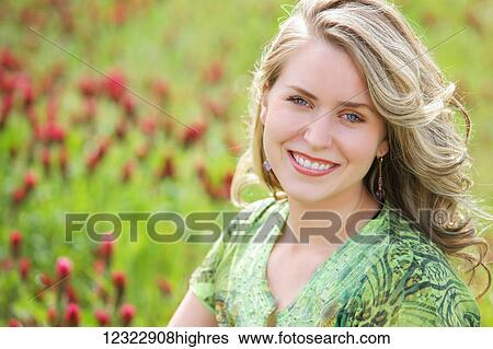 Stock Photograph - Portrait of a young woman with blond curly hair in a field of flowers; Oregon, United States of America. Fotosearch