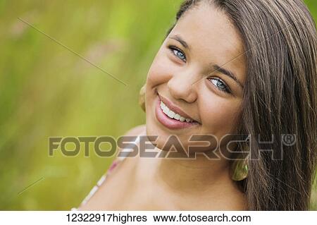 Stock Photograph - Portrait of a young woman with long, brown hair and bright blue eyes; Oregon, United States of America. Fotosearch