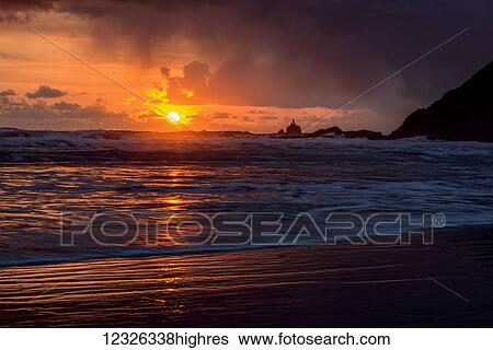Stock Photograph - Rain falls on the waves during a sunset on the Oregon Coast; Cannon Beach, Oregon, United States of America. Fotosearch