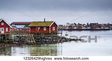 Red buildings along the water's edge under a cloudy sky; Lofoten Islands, Nordland, Norway View Large Photo Image Stock Photograph - Red buildings along the water's edge under a cloudy sky; Lofoten Islands, Nordland, Norway. Fotosearch
