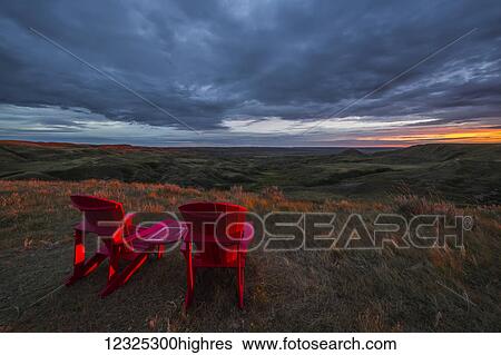 Stock Photograph - Red chairs overlooking Grasslands National Park; Val Marie, Saskatchewan, Canada. Fotosearch
