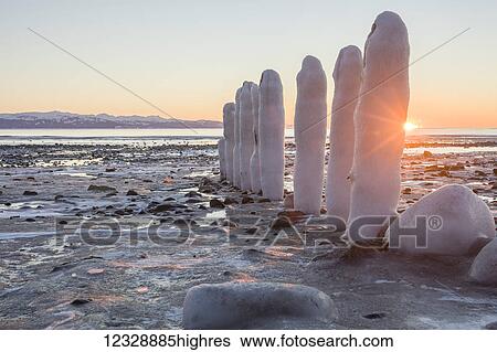 Rocks and pilings covered with snow and ice along the shore at the water's edge, with a view of the coastline and mountains in the distance; Alaska, United States of America View Large Photo Image Stock Photograph - Rocks and pilings covered with snow and ice along the shore at the water's edge, with a view of the coastline and mountains in the distance; Alaska, United States of America. Fotosearch