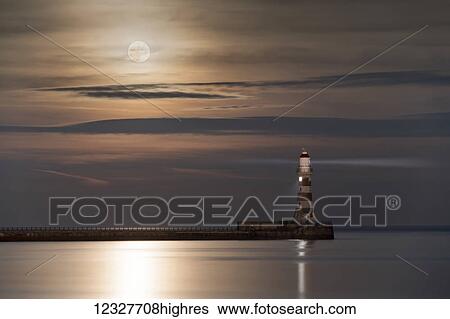 Roker Lighthouse glowing at the end of a pier under a bright full moon reflecting on tranquil water; Sunderland, Tyne and Wear, England View Large Photo Image Stock Photograph - Roker Lighthouse glowing at the end of a pier under a bright full moon reflecting on tranquil water; Sunderland, Tyne and Wear, England. Fotosearch