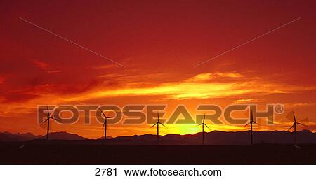 Stock Image - Row of wind turbines and sunset. Fotosearch