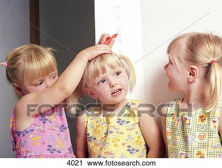 Stock Image - Sisters measuring height. Fotosearch