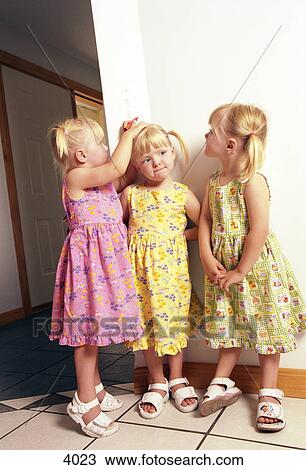 Stock Image - Sisters measuring height. Fotosearch