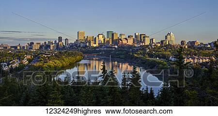 Stock Photograph - Skyline of downtown Edmonton reflected in the North Saskatchewan River under a blue sky; Edmonton, Alberta, Canada. Fotosearch