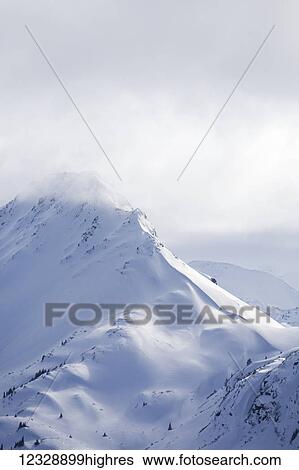 Stock Photograph - Snow covered Kenai Mountain peaks under clouds, Kachemak Bay State Park; Alaska, United States of America. Fotosearch