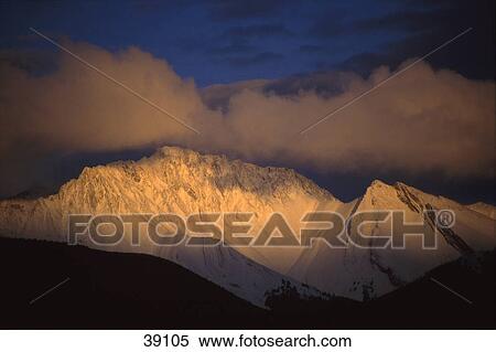 Stock Photography - Snow covered mountain with clouds. Fotosearch