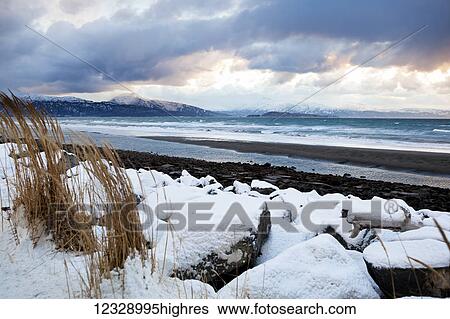 Stock Photograph - Snow on the rocks and grass along the shores of Kachemak Bay; Alaska, United States of America. Fotosearch