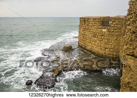 Stock Photograph - Stone wall along the water's edge with a view of the Mediterranean Sea; Haifa District, Israel. Fotosearch