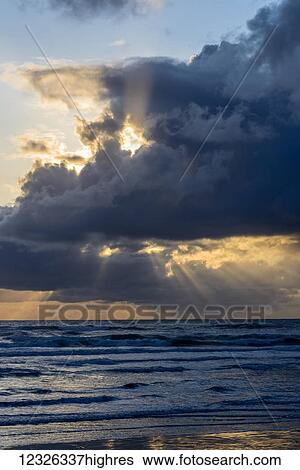 Stock Photograph - Sunbeams flow through holes in the clouds along the Oregon Coast; Cannon Beach, Oregon, United States of America. Fotosearch