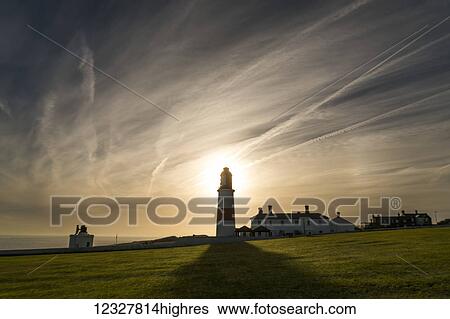 Sunlight behind a lighthouse casts a shadow on a grass field along the coast; South Shields, Tyne and Wear, England View Large Photo Image Stock Photograph - Sunlight behind a lighthouse casts a shadow on a grass field along the coast; South Shields, Tyne and Wear, England. Fotosearch