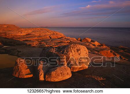 Sunset light bathes a rocky shoreline and distant lighthouse; Sambro Island, Nova Scotia, Canada View Large Photo Image Stock Photograph - Sunset light bathes a rocky shoreline and distant lighthouse; Sambro Island, Nova Scotia, Canada. Fotosearch