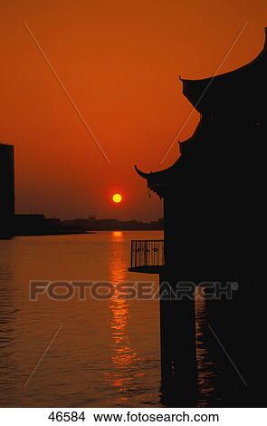 Picture - Sunset over river with silhouette of pagoda roof. Fotosearch
