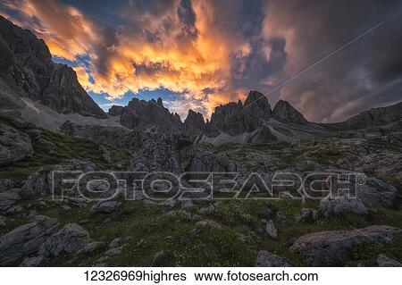 Stock Photograph - Sunset over the Dolomite Mountains of Italy, with beautiful coloured clouds; Cortina, Italy. Fotosearch