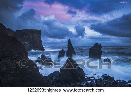 Stock Photograph - Sunset over the wild ocean along the southwest coast of Iceland; Iceland. Fotosearch