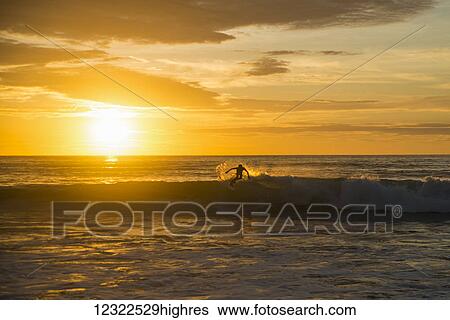 Surfer riding a wave at sunset, Dreamland beach; Bali Island, Indonesia View Large Photo Image Stock Photograph - Surfer riding a wave at sunset, Dreamland beach; Bali Island, Indonesia. Fotosearch