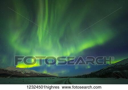 Stock Photograph - The aurora borealis glows over the frozen Richardson Highway on a bitterly cold night near Black Rapids in the Alaska Range; Alaska, United States of America. Fotosearch