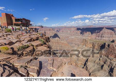 Stock Photograph - The beautiful viewpoint at the West Grand Canyon Skywalk attraction, a group of tourists enjoys the skywalk while other tourists take photos on the edge of the canyon cliffs; Arizona, United States of America. Fotosearch