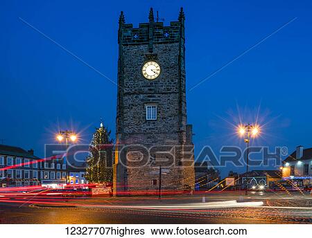 The clock in a tower and lamp posts glow with illumination at dusk, with light trails on the street; Richmond, Yorkshire, England View Large Photo Image Stock Photograph - The clock in a tower and lamp posts glow with illumination at dusk, with light trails on the street; Richmond, Yorkshire, England. Fotosearch