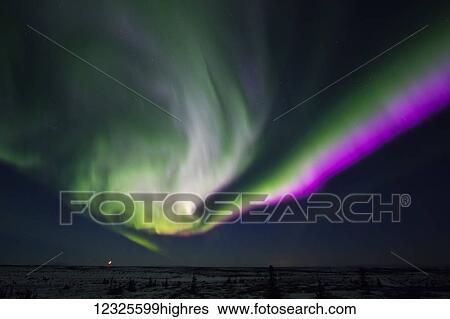 Stock Photograph - The crescent moon sets along the horizon beneath a vivid aurora borealis display; Alaska, United States of America. Fotosearch