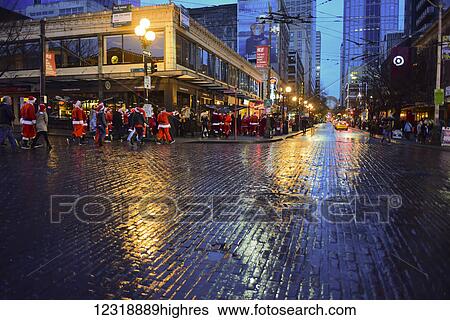 Stock Photograph - The Drunk santas Christmas party, a traditional annual gathering of hundreds of jolly Christmas revelers bar hopping through downtown Seattle including making a stop at the world famous Pike Place Public Market; Seattle, Washington, United States. Fotosearch